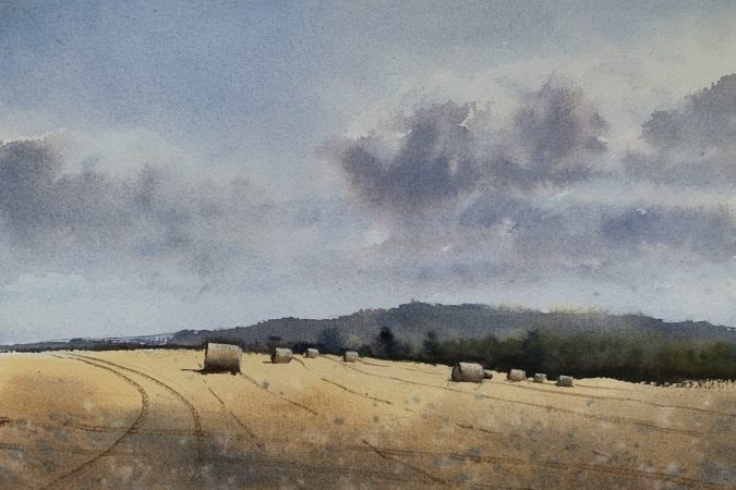Watercolour painting of a Sussex field with hay bales and distant trees and hills in the background by artist John Haywood